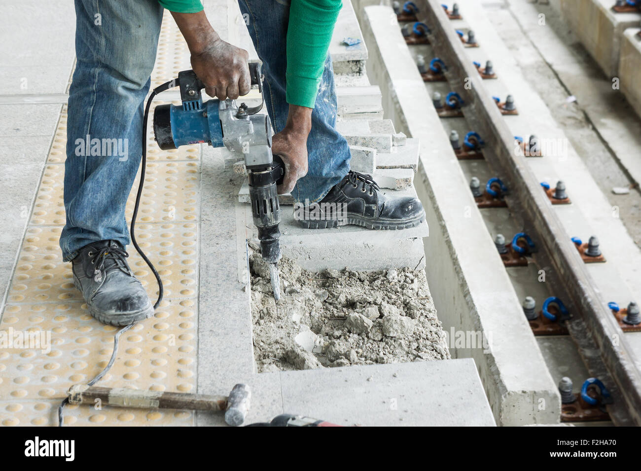 Lavoratore con martello pneumatico attrezzatura di perforazione rompendo pavimento in calcestruzzo al sito in costruzione Foto Stock