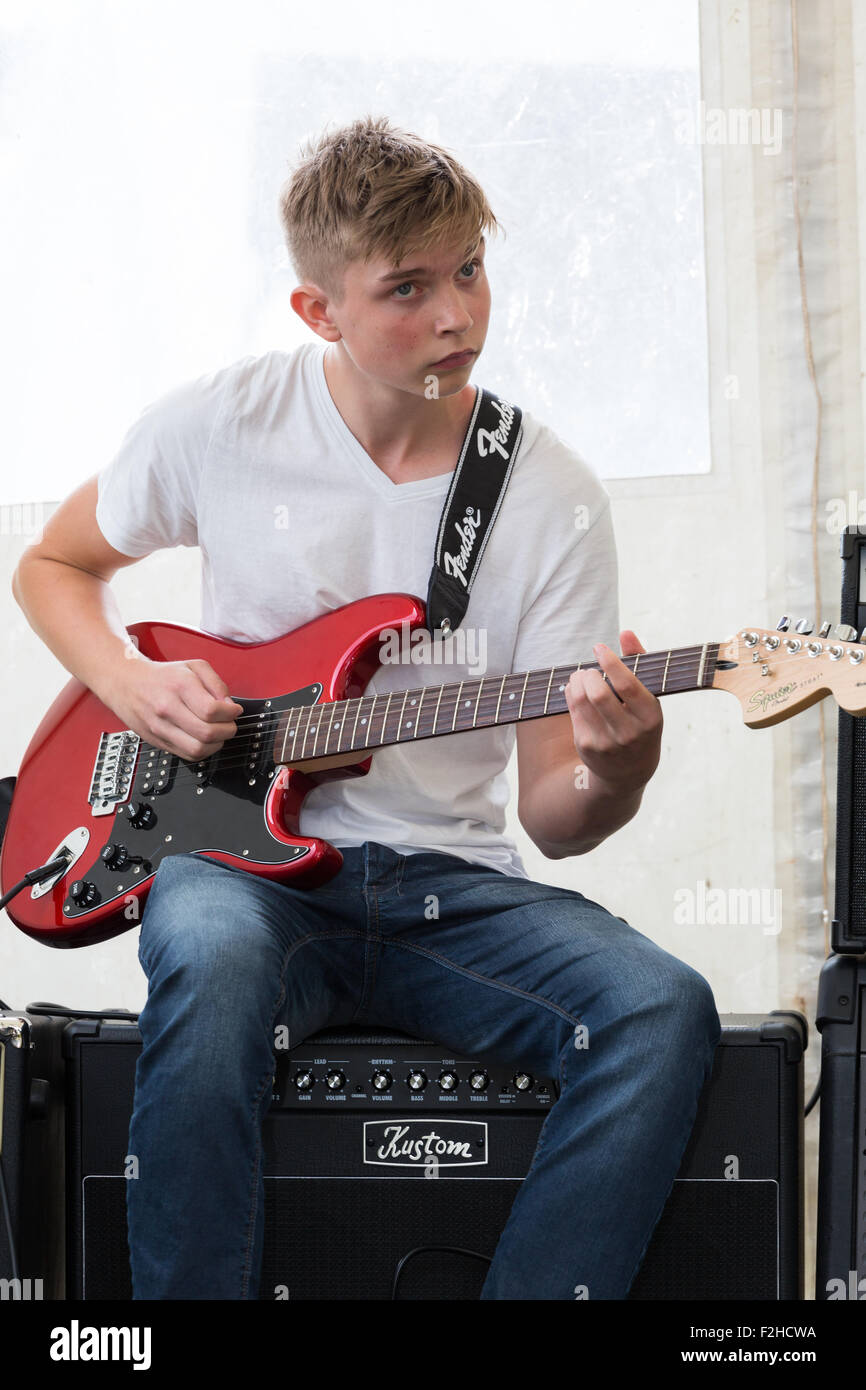 Un giovane maschio (boy) rock chitarrista seduto su un amp a suonare la chitarra elettrica Foto Stock