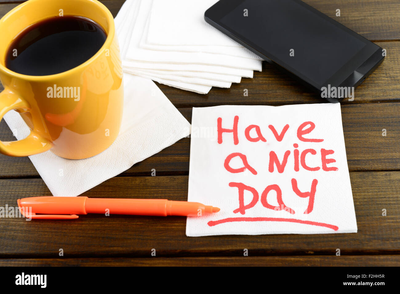 Hanno un bel giorno la scrittura sul tovagliolo bianco intorno a penna di caffè e telefono sul tavolo di legno Foto Stock