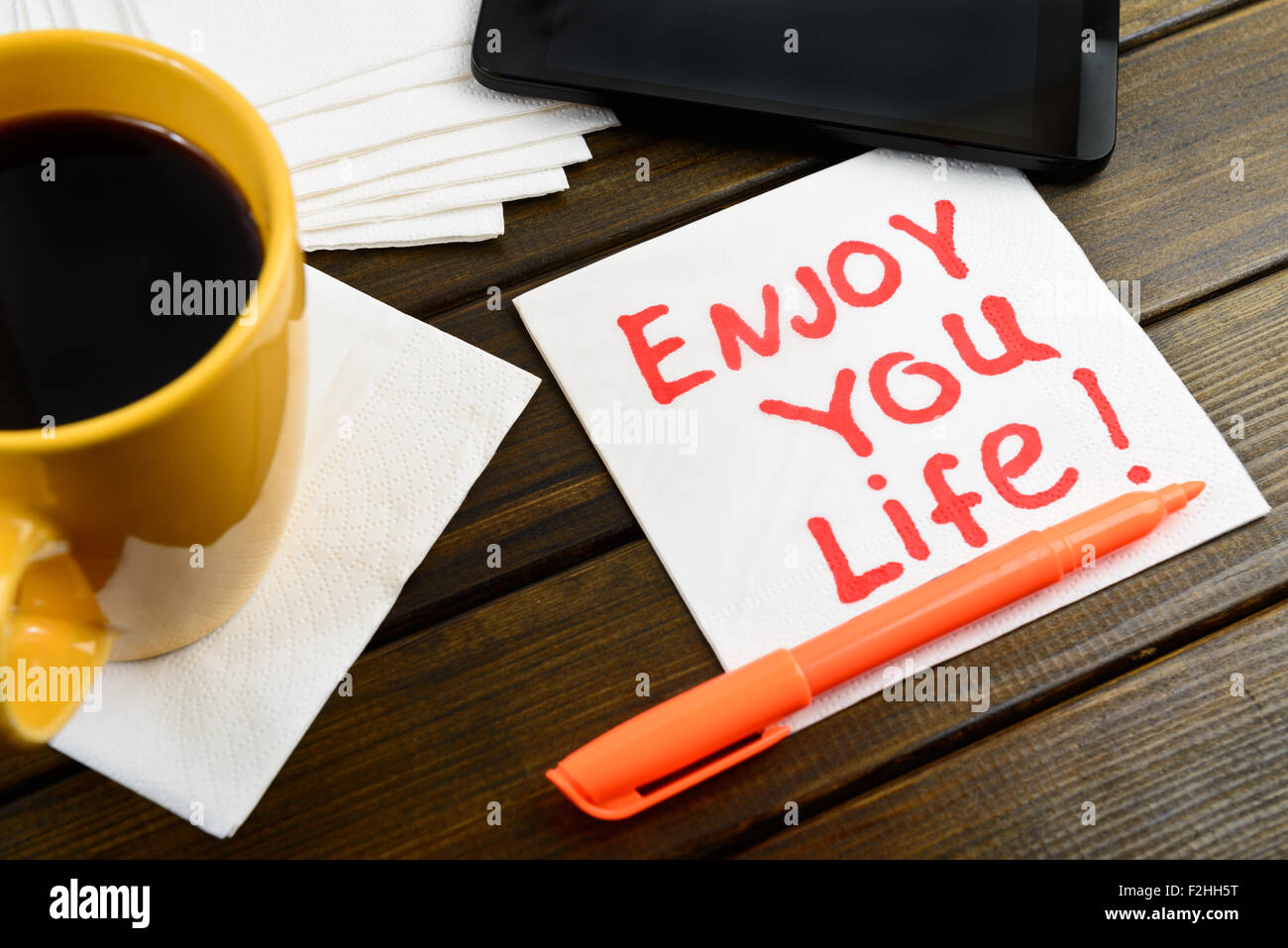 Godetevi la vostra vita la scrittura sul tovagliolo bianco intorno a penna di caffè e telefono sul tavolo di legno Foto Stock