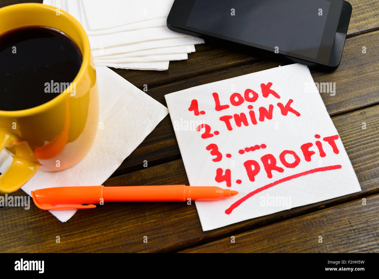 Cercare pensare il profitto la scrittura sul tovagliolo bianco intorno a penna di caffè e telefono sul tavolo di legno Foto Stock