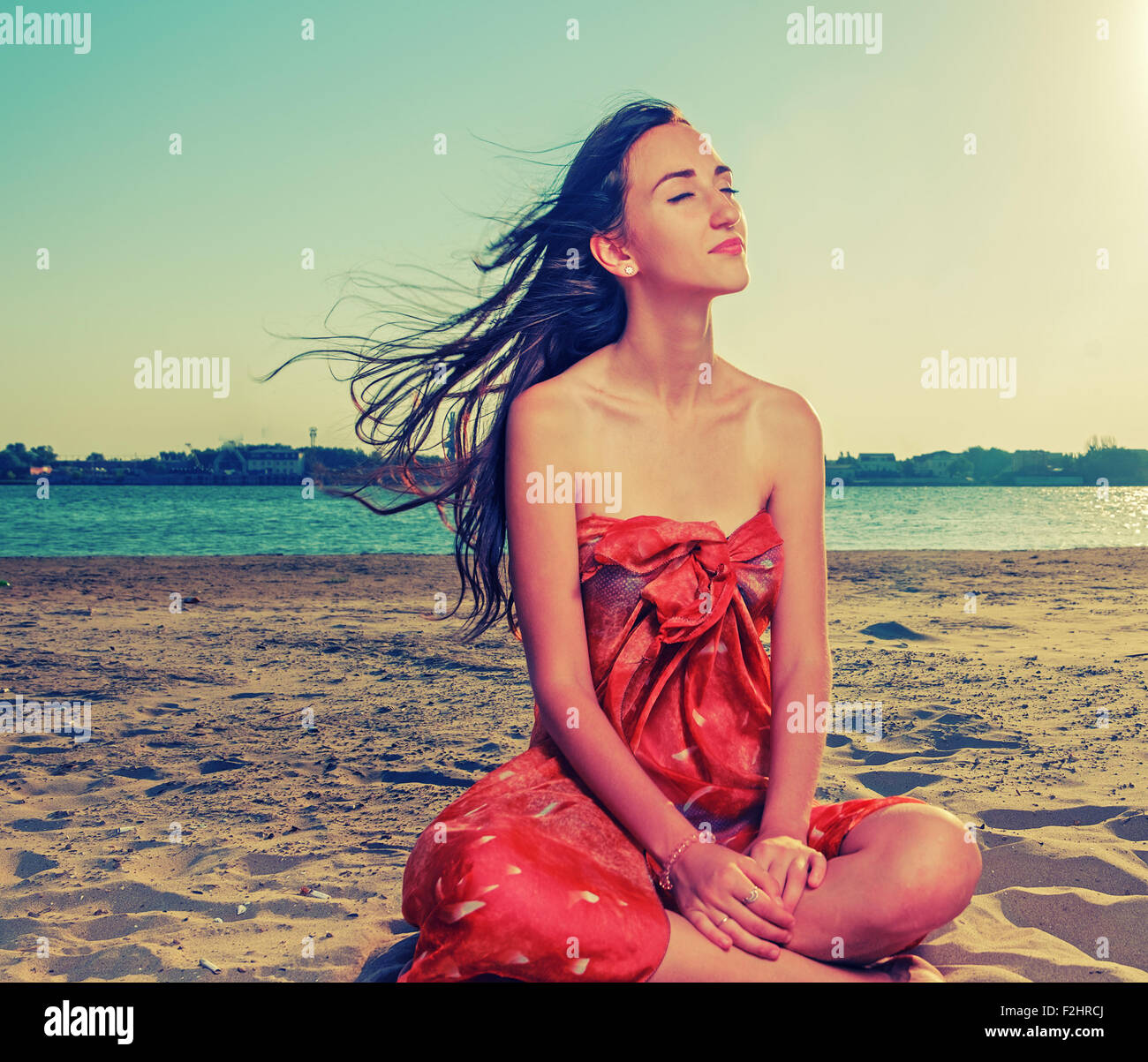 Capelli lunghi brunette meditare sulla spiaggia sabbiosa con capelli lusinghiero volare con il vento Foto Stock