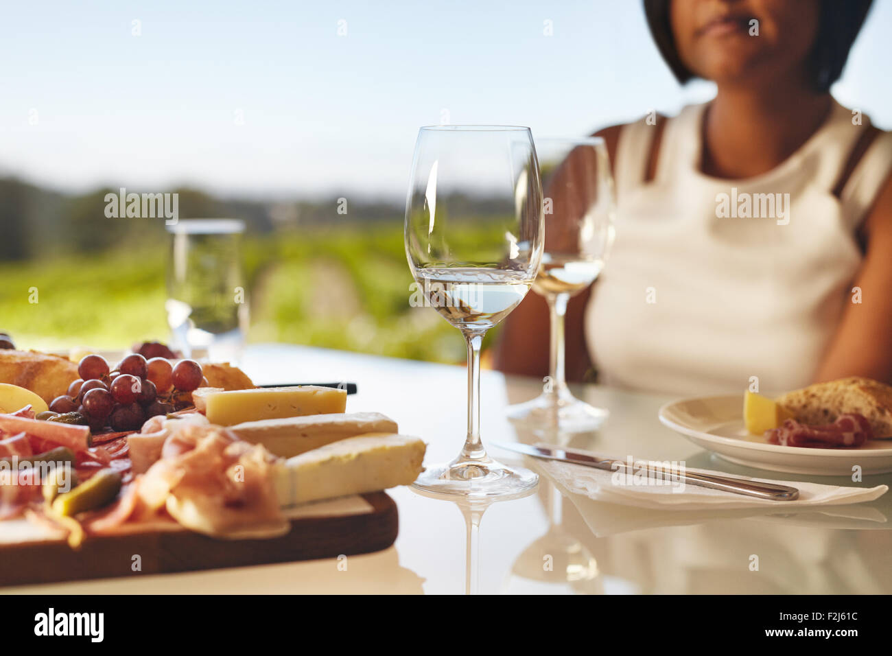 Tabella riportata in cantina con due bicchieri di vino, formaggio e uva. Donna seduta nel retro al ristorante cantina tabella. Foto Stock