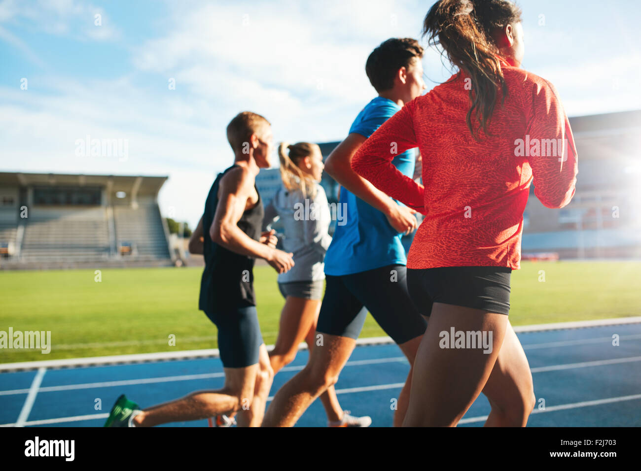Vista posteriore dei giovani in esecuzione insieme sulla pista. I giovani atleti praticanti un eseguito su Athletics Stadium via. Foto Stock