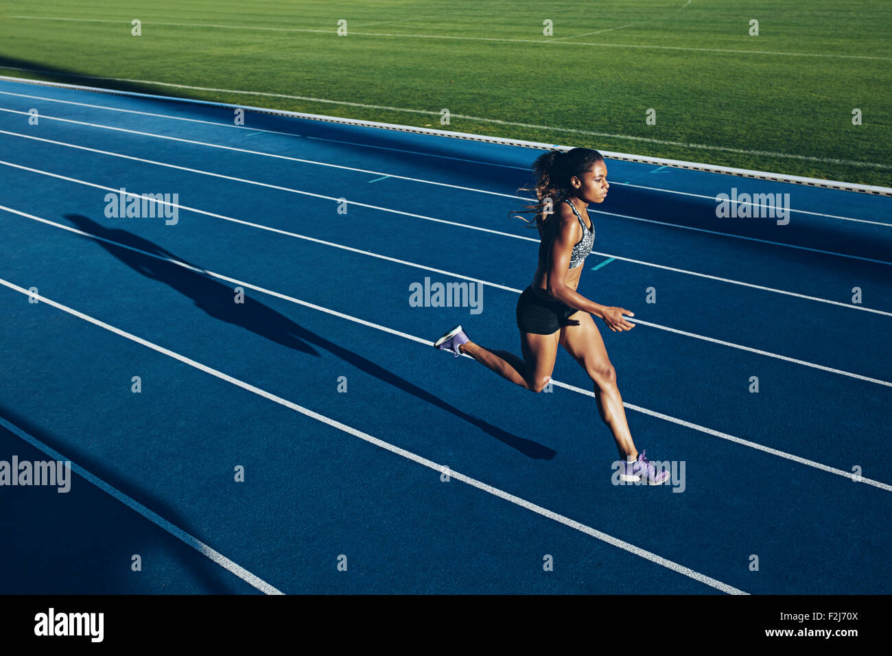 Colpo all'aperto della giovane donna africana atleta che corre sulla pista. Professional sportive durante l esecuzione di una sessione di formazione. Foto Stock