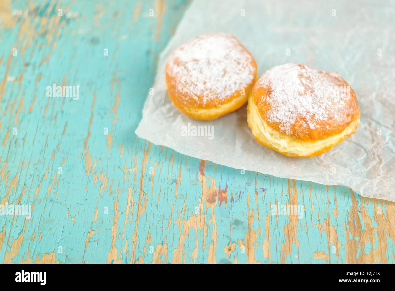 Dolce ciambelle zuccherino in legno rustico tavolo da cucina, forno gustose ciambelle accartocciata sulla carta da forno in vintage retrò immagine dai toni Foto Stock