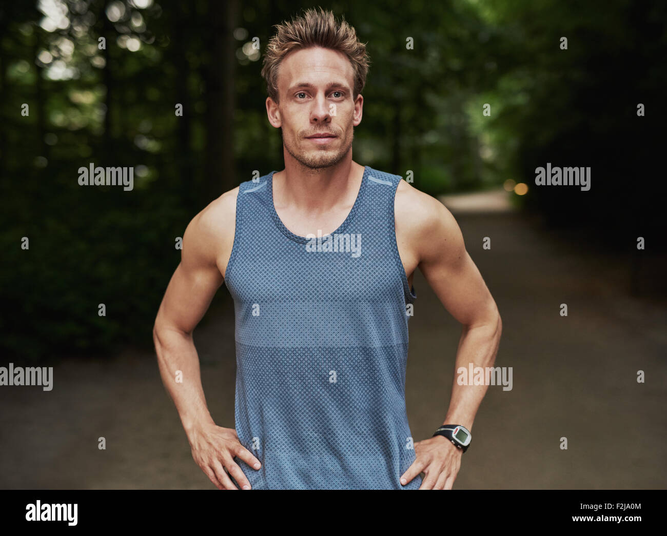 Mezzo Corpo colpo di una Preparazione Atletica Giovane uomo in piedi al parco con le mani sulla cintura e guardando in lontananza. Foto Stock