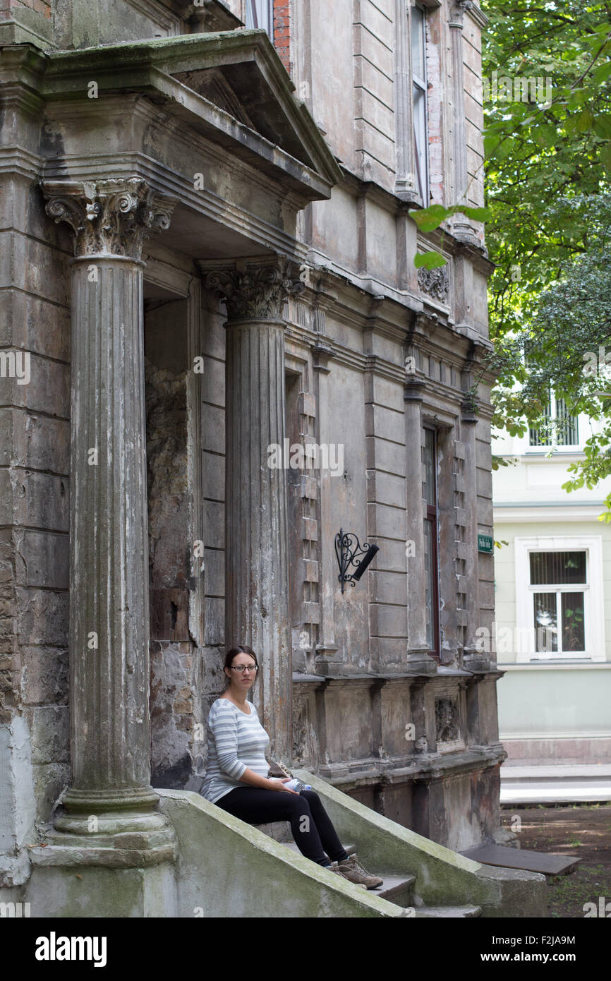 Vecchio edificio con una ragazza seduta sulle scale Foto Stock
