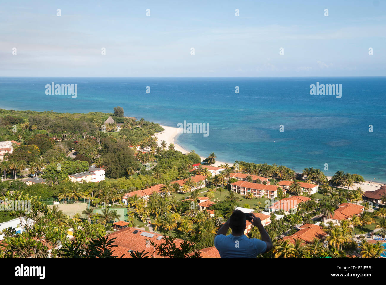 Un uomo prende una fotografia del Breezes Jibacoa resort da una collina lookout in Cuba Foto Stock