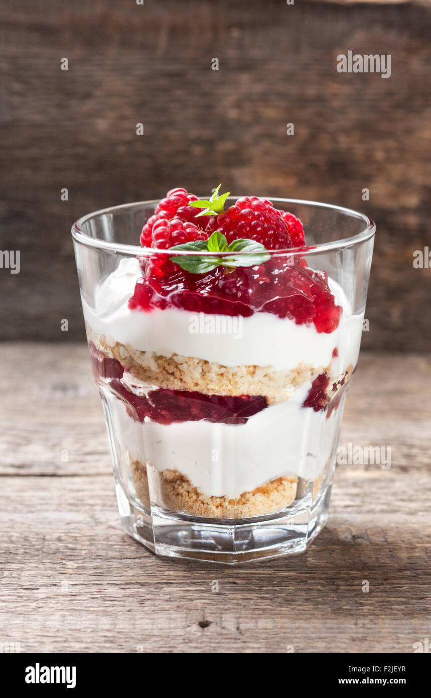 Cheesecake con lamponi, menta in vetro sul vecchio sfondo di legno Foto Stock