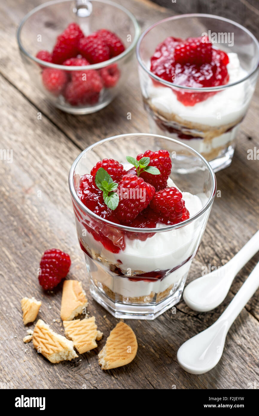 Cheesecake con lamponi, menta in vetro sul vecchio sfondo di legno Foto Stock
