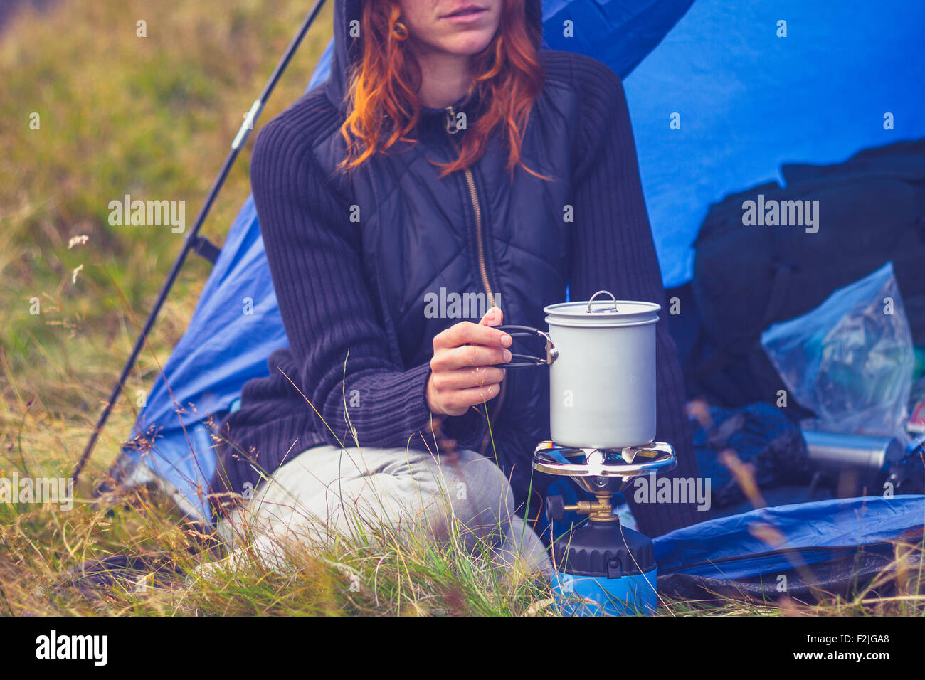 Giovane donna in tenda cucina con fornello da campeggio Foto Stock