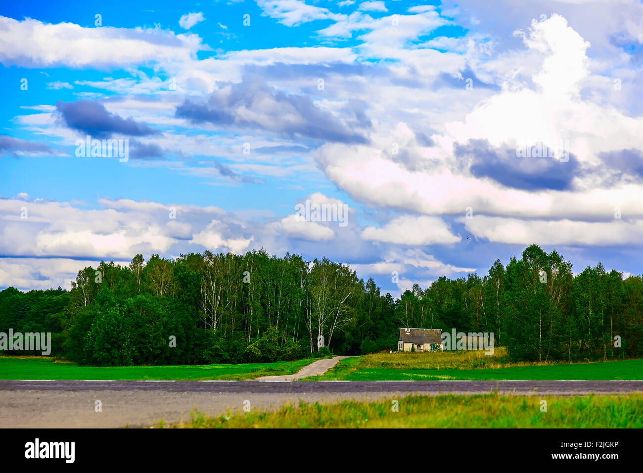 Paesaggio con casa singola vicino alla strada in verde di alberi con cielo blu e nuvole Foto Stock