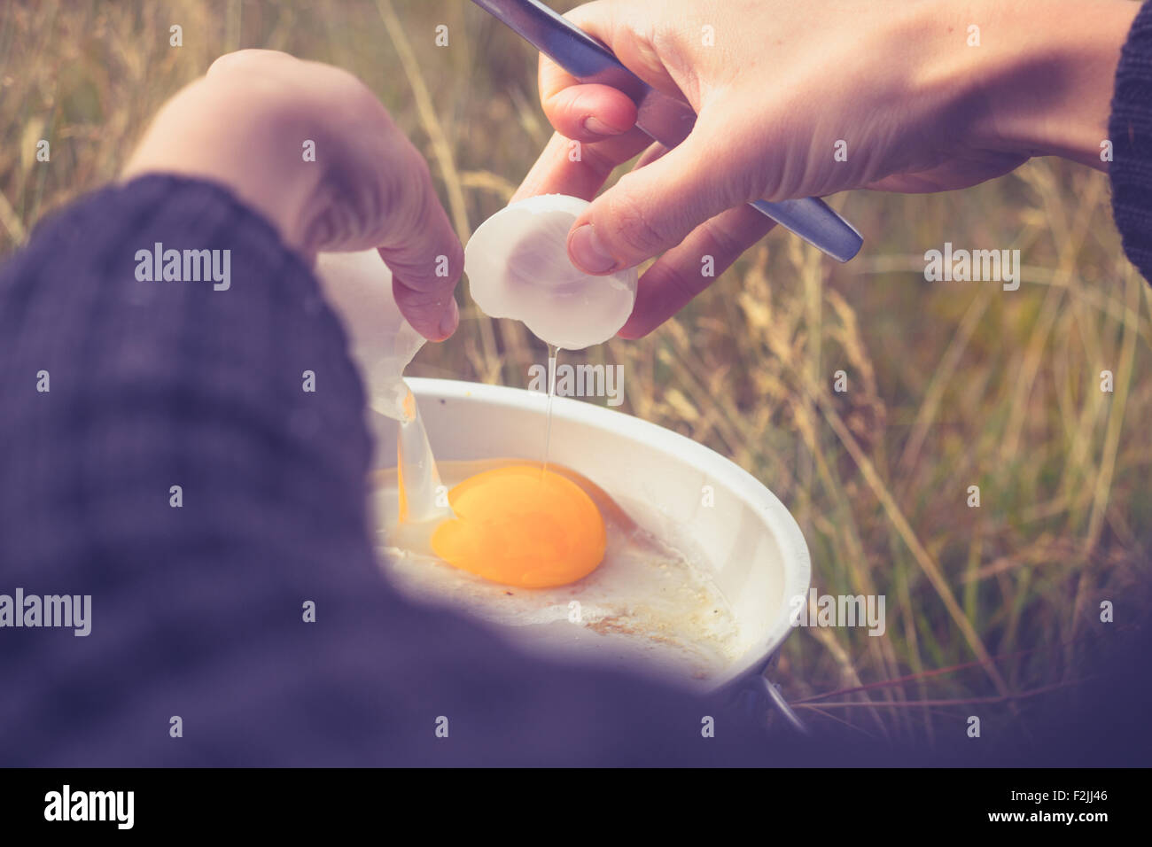 Le mani della giovane donna per la cottura delle uova in natura Foto Stock