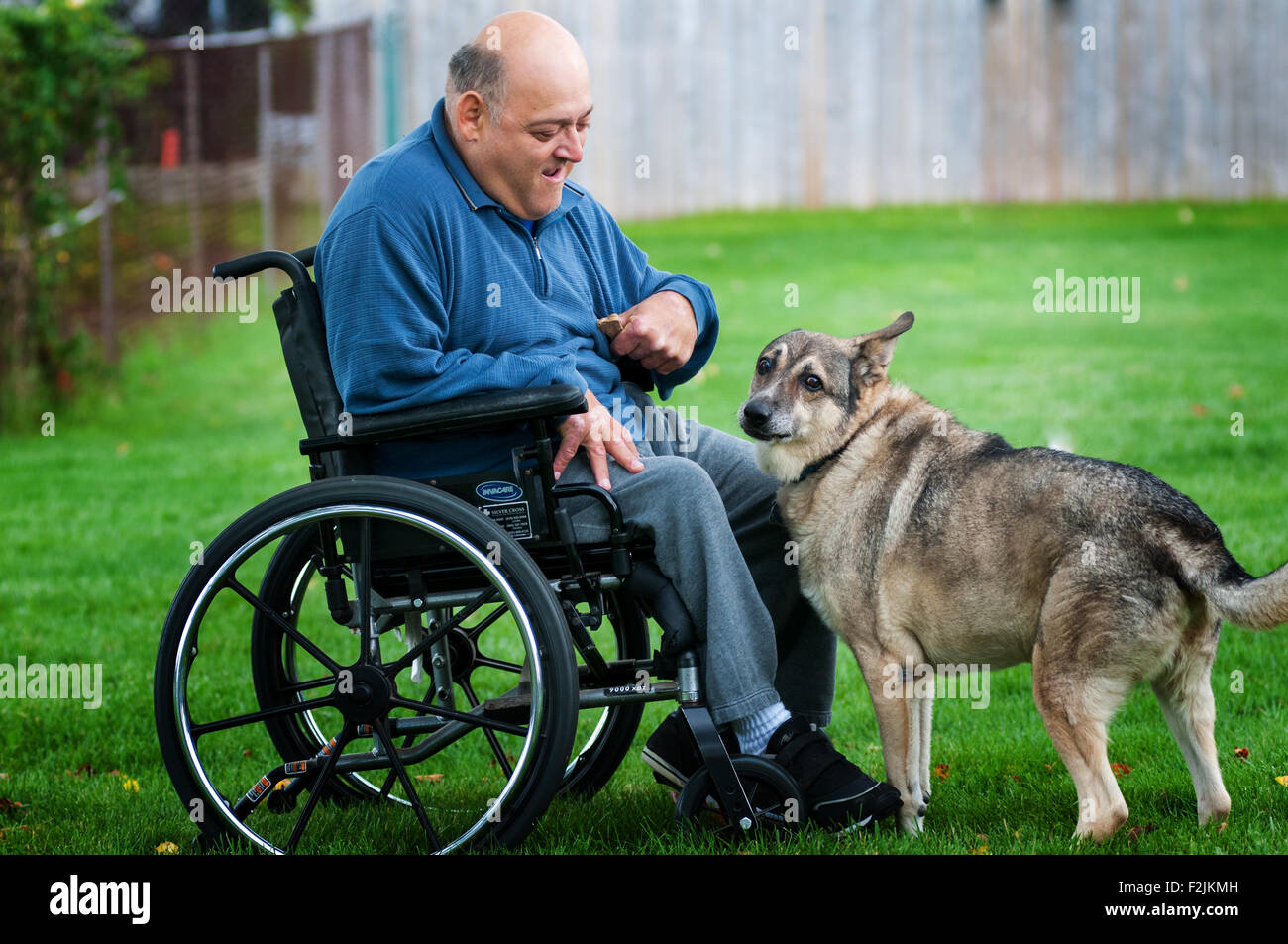 Uomo in una sedia a rotelle e il suo cane Foto Stock