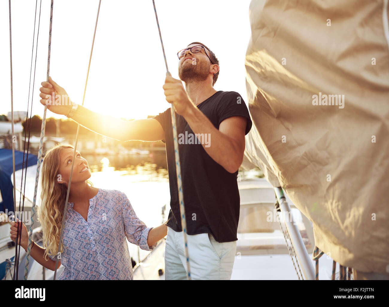 Giovane sulla loro barca vela il controllo prima di uscire Foto Stock