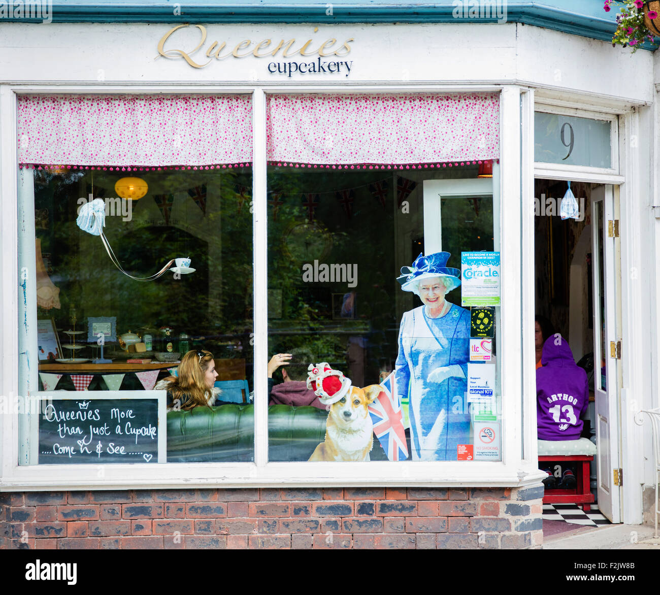 Queenies Cupcakery sale da tè in Ironbridge Staffordshire REGNO UNITO con un ritaglio di cartone della regina Elisabetta con il suo cane corgi Foto Stock