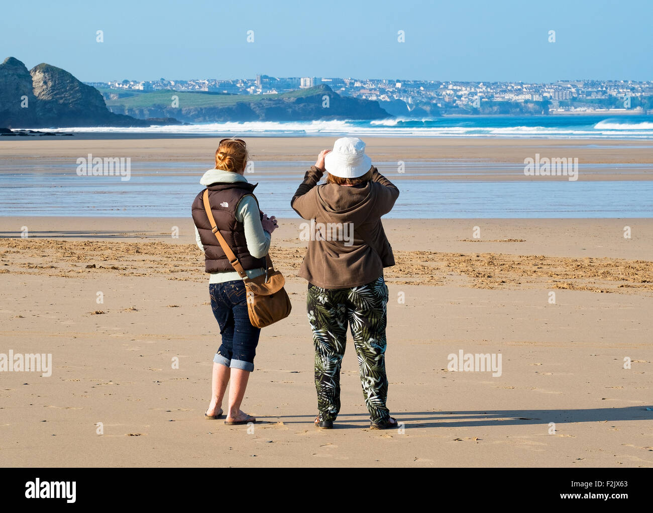 Due giovani donne scattano fotografie sulla spiaggia a Watergate Bay in cornwall, Regno Unito Foto Stock