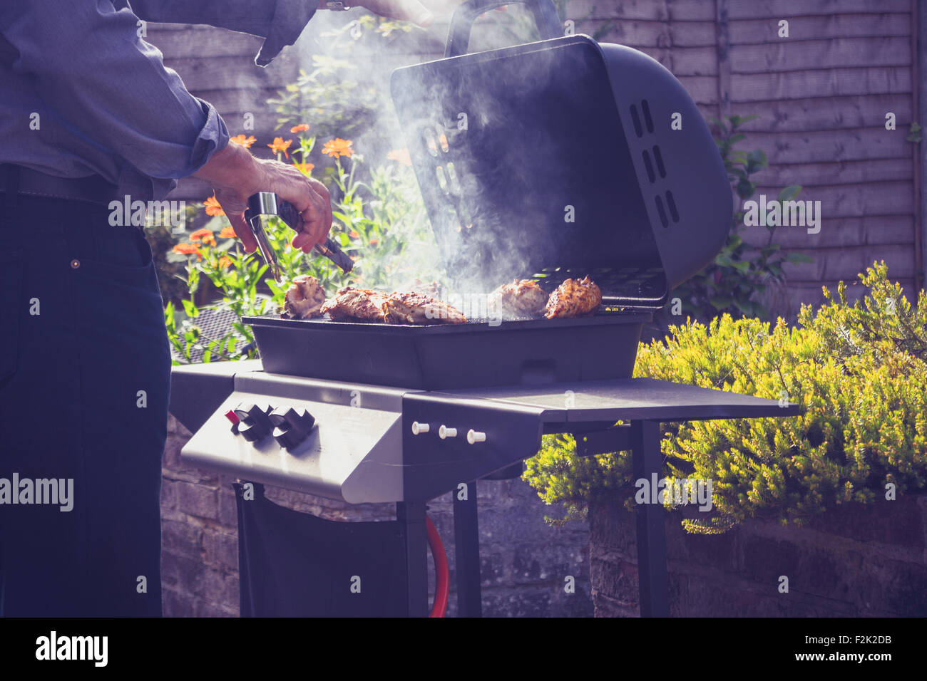 Uomo Senior per la cottura barbecue esterno Foto Stock