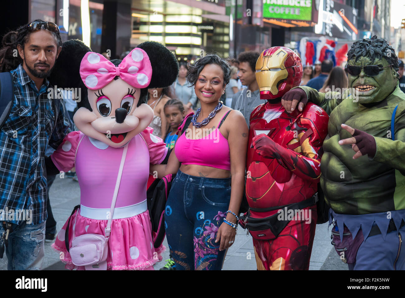 Un giovane pone per fotografie con artisti di strada vestiti come Minnie Mouse, uomo del ferro e la carcassa in Times Square a New York City. Foto Stock