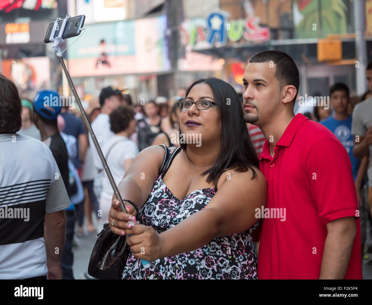 Una giovane coppia prende un selfie con un bastone selfie durante la visita a Times Square a New York City. Foto Stock