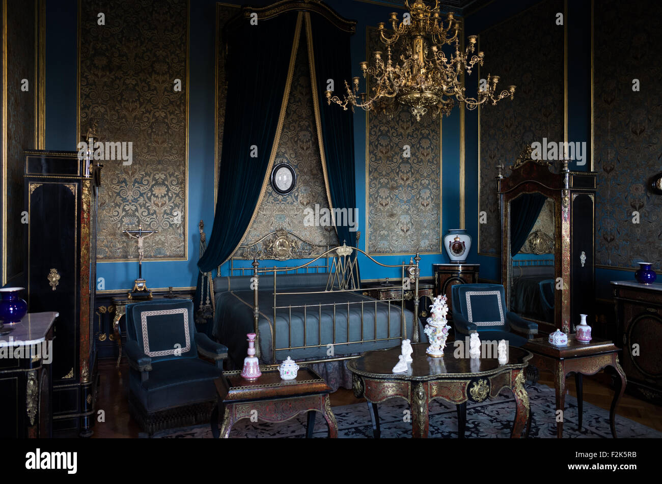 Castello di Chapultepec Camera di Carlota Città del Messico Messico | CITTÀ DEL MESSICO, Messico — La camera di Carlota nel Castello di Chapultepec mostra l'arredamento interno blu e oro del Secondo Impero Messicano, centrato su un letto a baldacchino in ottone drappeggiato. Progettato tra il 1864 e il 1866 durante il regno dell'imperatore Massimiliano I, i quartieri residenziali imperiali presentano una ricca tappezzeria murale in damasco blu incorniciata da modanature dorate. L'influenza architettonica europea della stanza è evidente nei mobili in stile Boulle, che utilizzano intricate intarsi in tartaruga e ottone, e il letto centrale che porta il nome di Massimiliano' Foto Stock