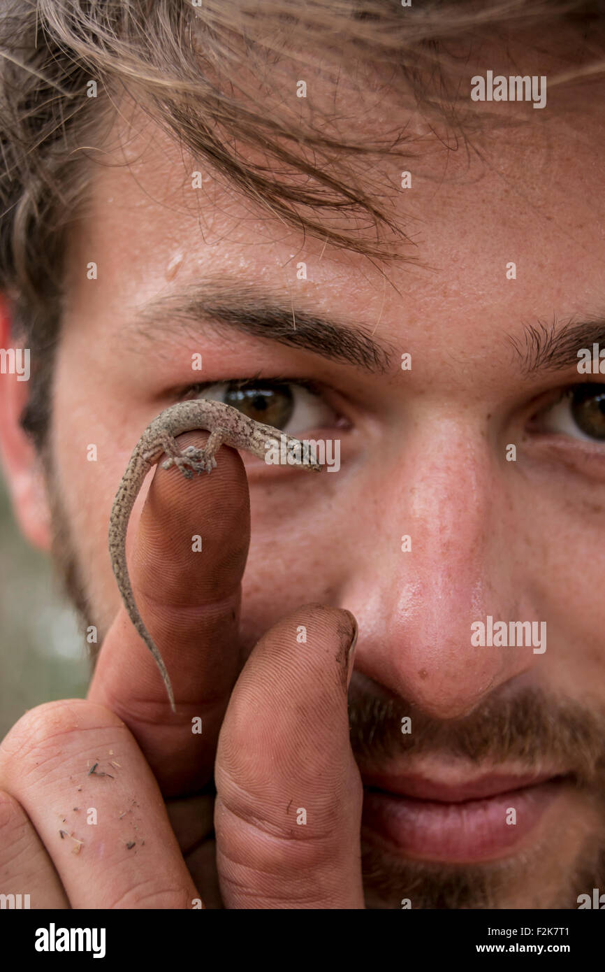 Close up di un il volto dell'uomo con una piccola lucertola sul suo dito accoglieva Foto Stock