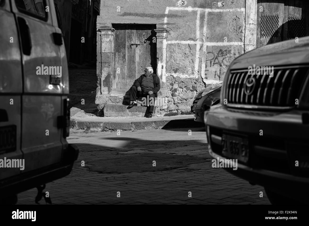 LEONFORTE, Italia - Gennaio, 08: il vecchio uomo seduto sul gradino della porta vecchia su gennaio 08, 2014 Foto Stock