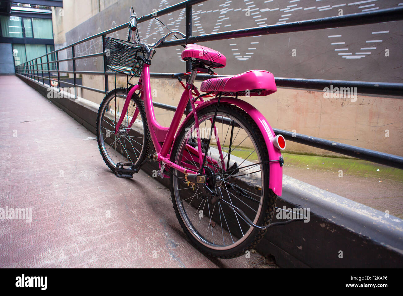 Vista della bicicletta rosa accanto alla ringhiera in ferro Foto Stock