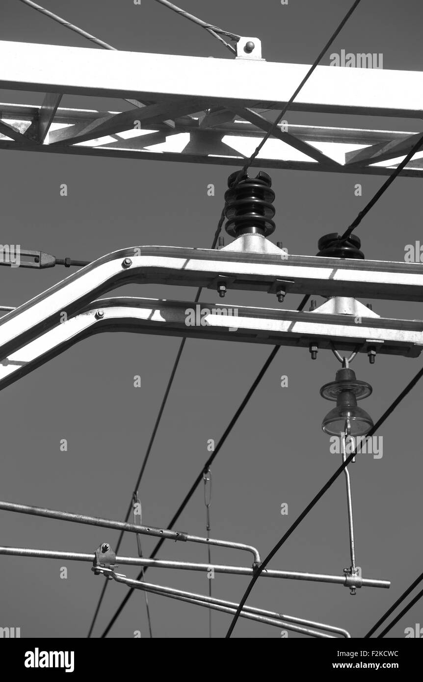 Impianto elettrico della trasmissione di energia per ferrovia isolata contro sky in bianco e nero in verticale Foto Stock