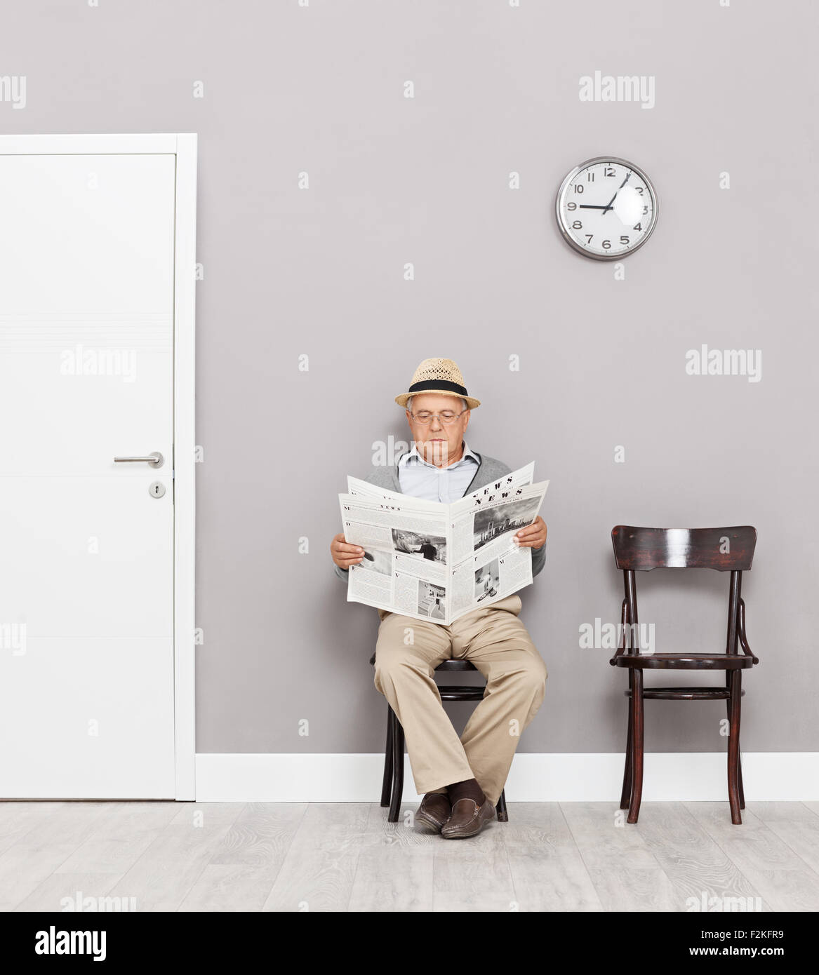 Senior gentleman seduti su sedie di legno in una sala di attesa e la lettura di un quotidiano shot con inclinazione e spostamento lente Foto Stock