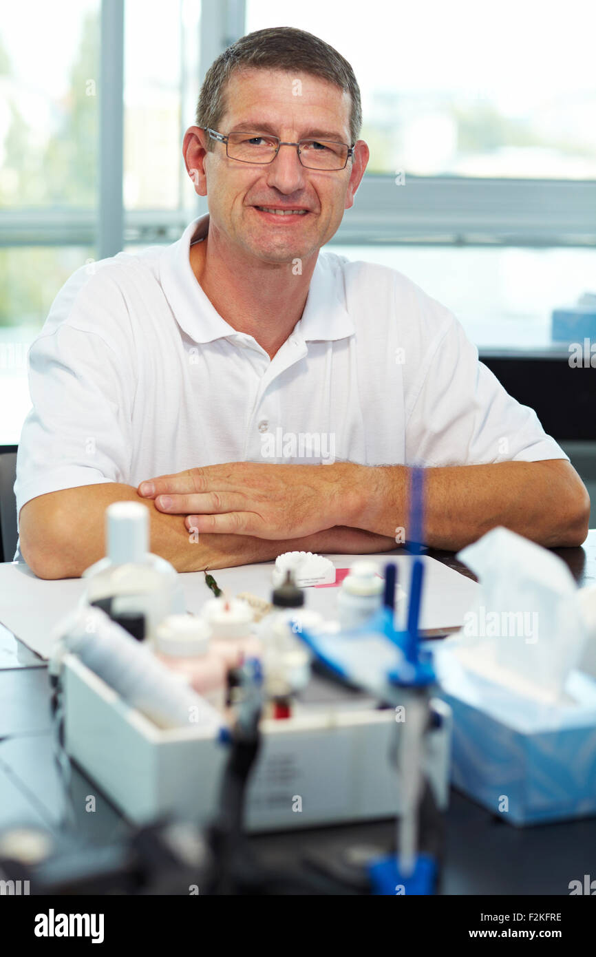 Odontotecnico sorridente sul suo spazio di lavoro in un laboratorio Foto Stock