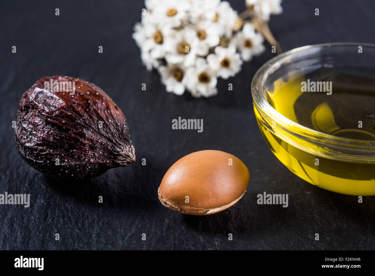 Olio di Argan e frutti su sfondo nero Foto Stock