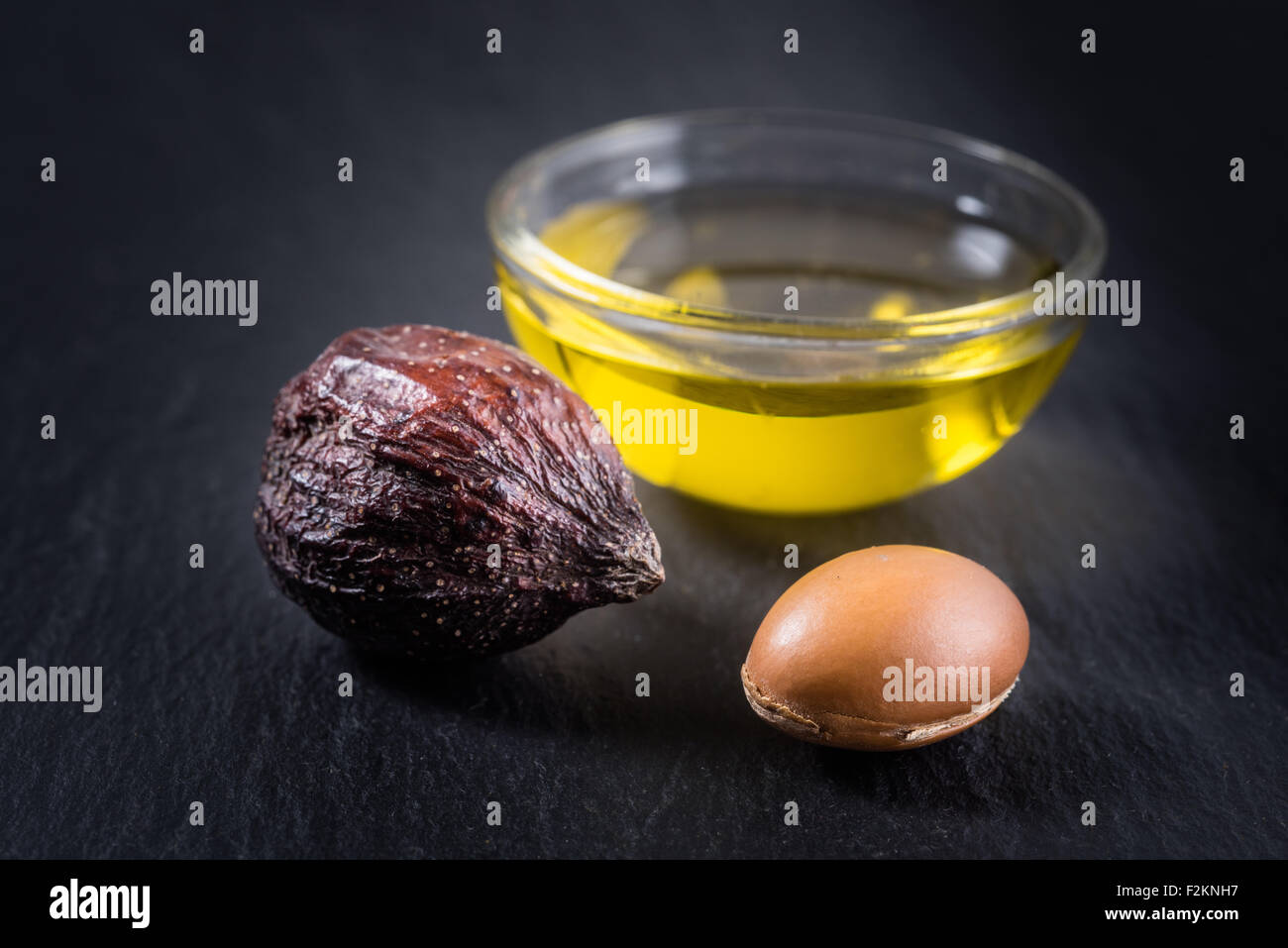 Olio di Argan e frutti su sfondo vlack Foto Stock