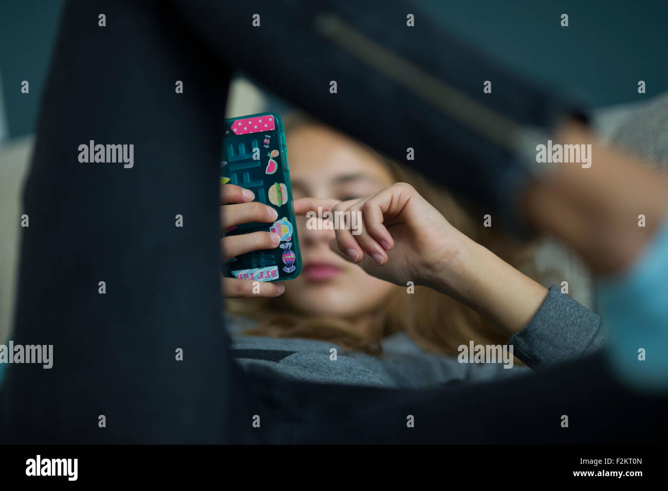 Ragazza giovane rilassarsi con il suo smartphone su un divano Foto Stock