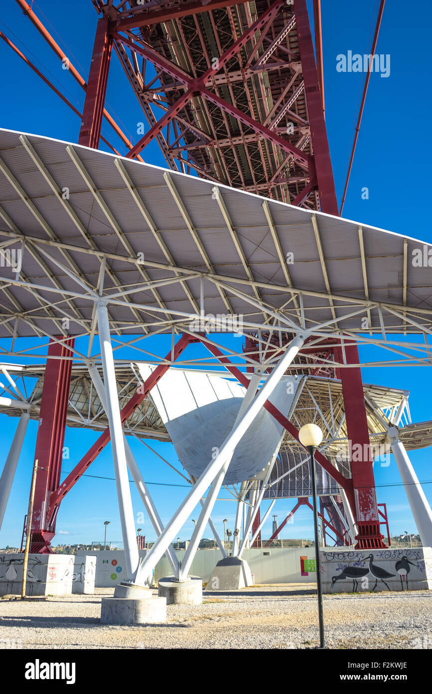 Vista parte inferiore della protezione solare scultura e di Lisbona 25 de Abril Bridge. Foto Stock