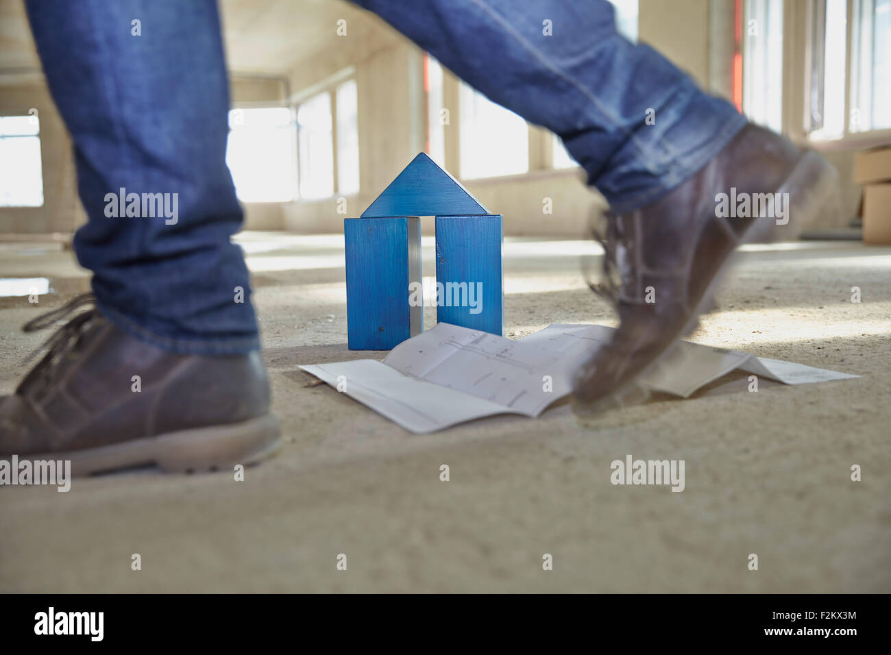 Uomo che cammina con il modello casa fatta di mattoni di edificio su un sito in costruzione Foto Stock