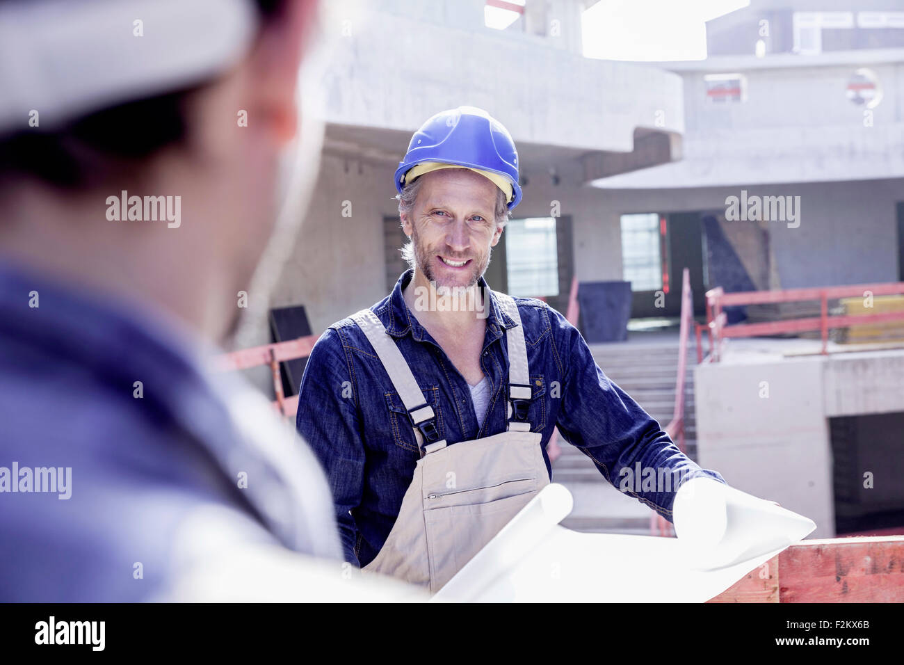 Due lavoratori sul sito di costruzione con piano di costruzione Foto Stock