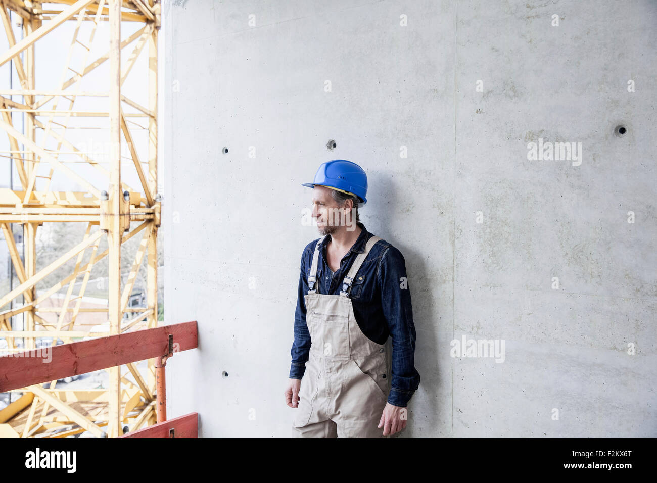Lavoratore sul sito in costruzione permanente al muro di cemento Foto Stock