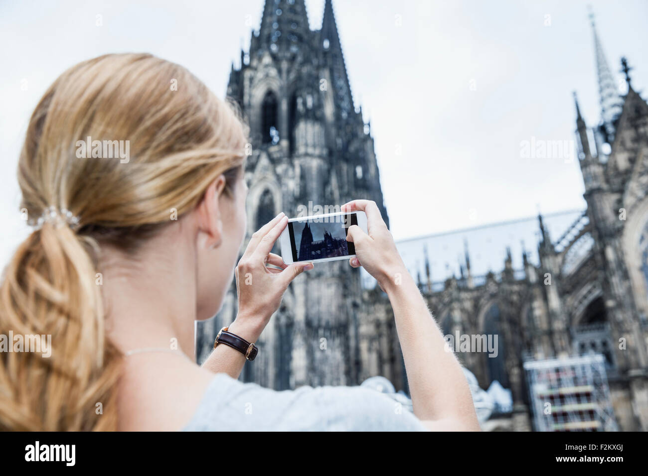 Germania, Colonia, giovane donna di scattare una foto della Cattedrale di Colonia con lo smartphone Foto Stock