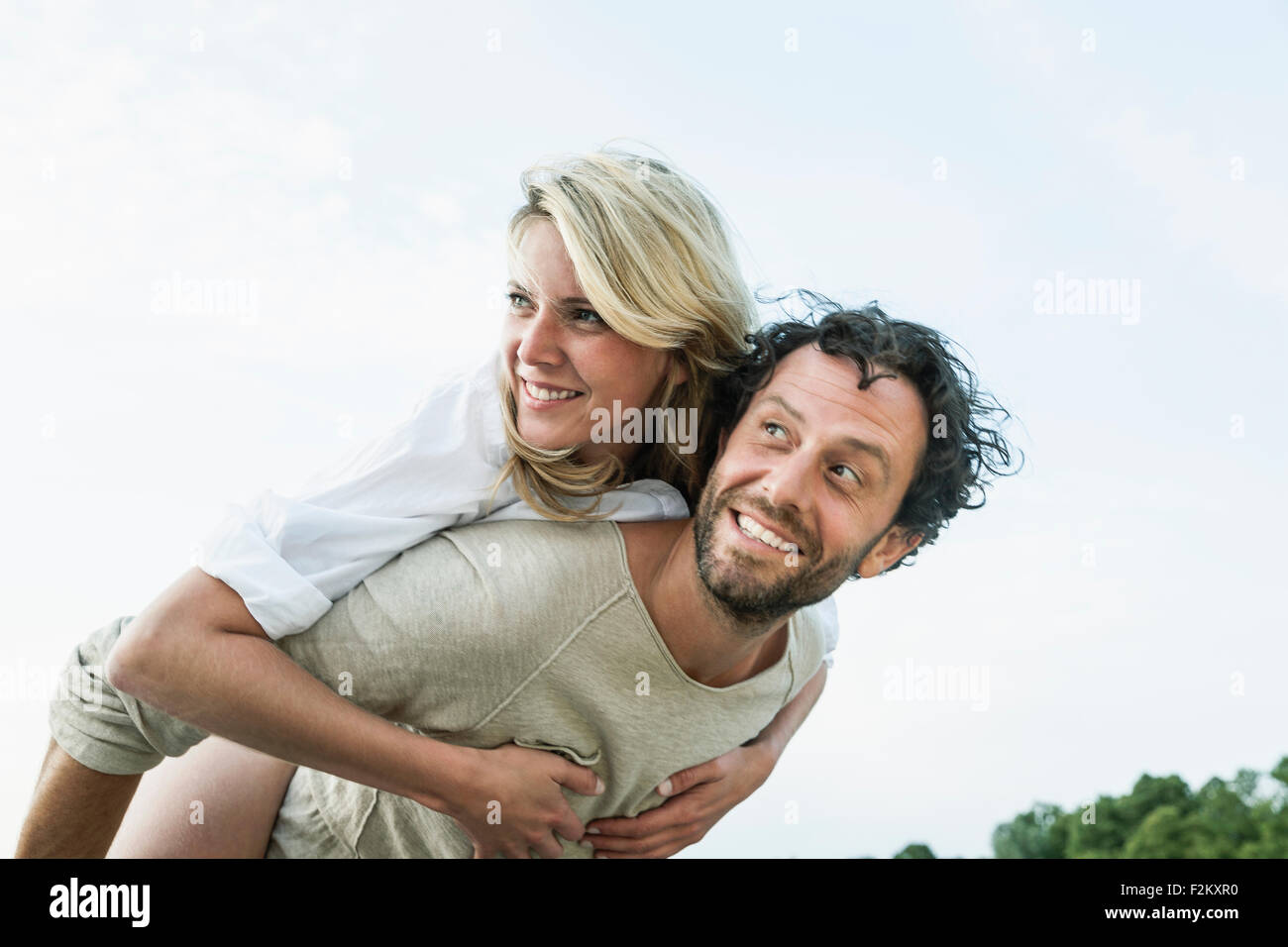 Uomo sorridente che trasportano donna piggyback Foto Stock