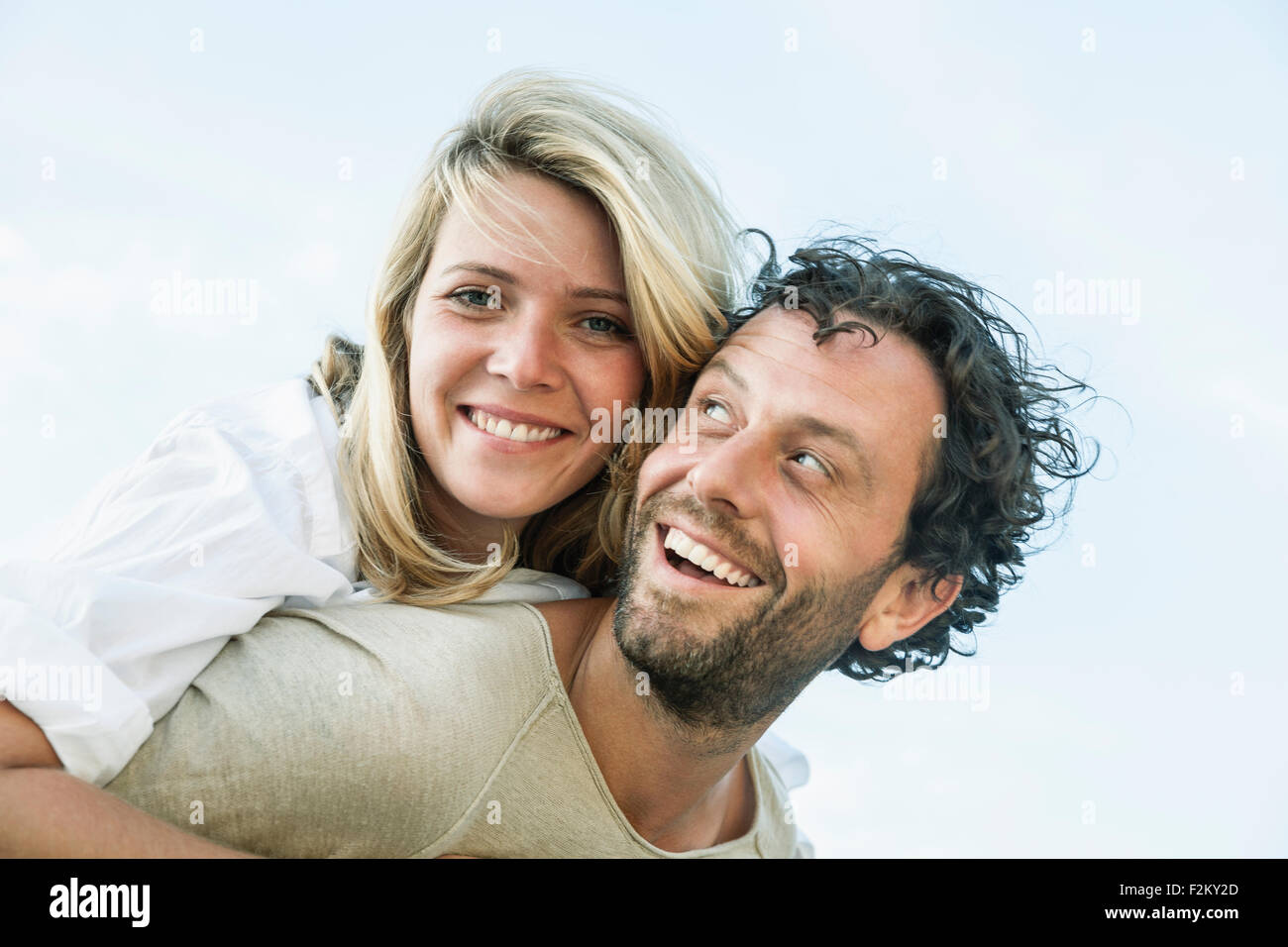 Uomo sorridente che trasportano donna piggyback Foto Stock