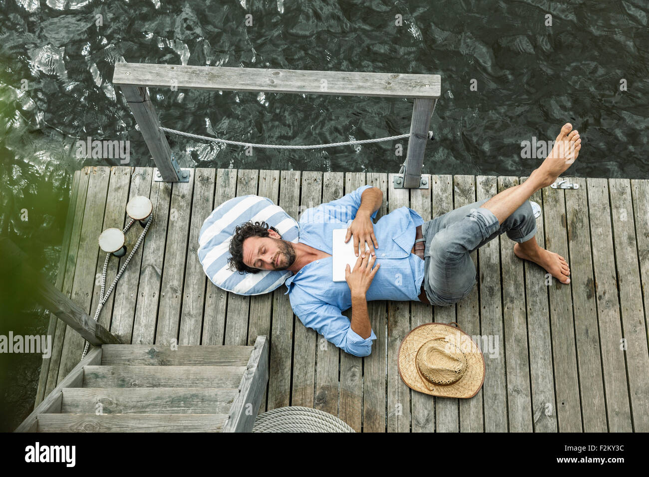 Uomo disteso su piattaforma in the waterside Foto Stock