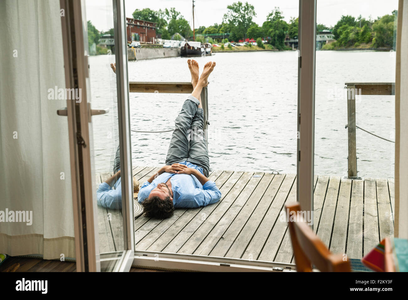 Uomo disteso sul ponte di legno di una barca casa Foto Stock