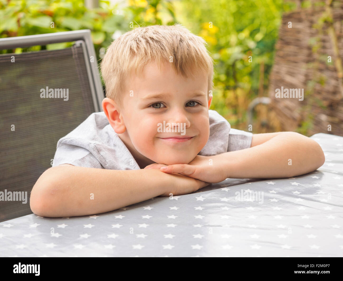 Ritratto di sorridente ragazzo biondo seduti sulla terrazza Foto Stock