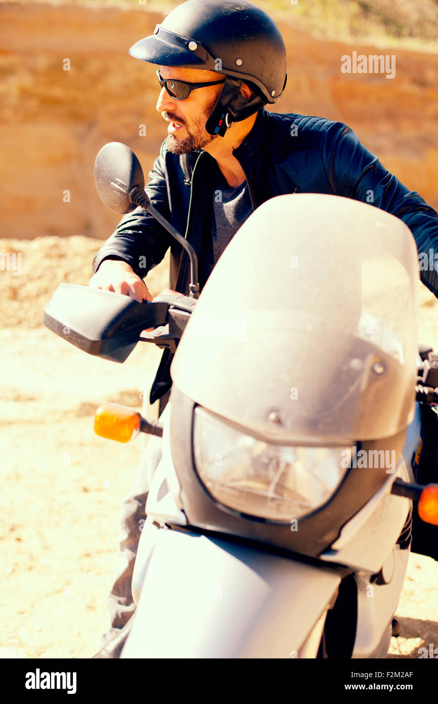 Uomo maturo con bici del motore nella buca di sabbia Foto Stock