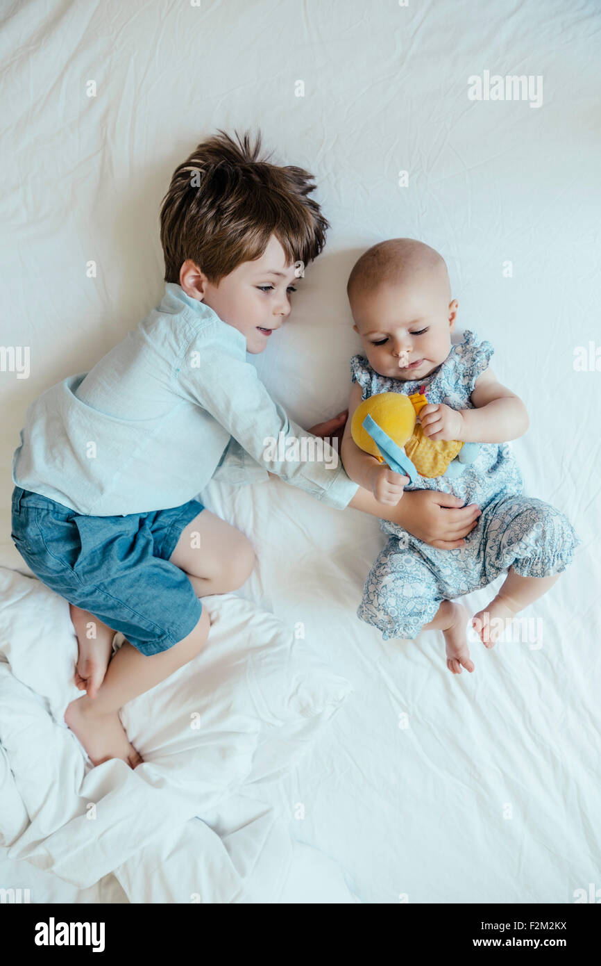 Baby girl e fratello affiancati sul letto Foto Stock