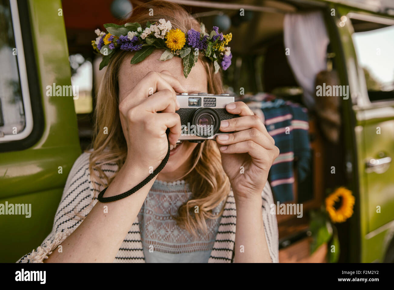 Hippie donna di scattare una foto con la telecamera analogica davanti a van Foto Stock Hippie donna di scattare una foto con la telecamera analogica davanti a van Foto Stock