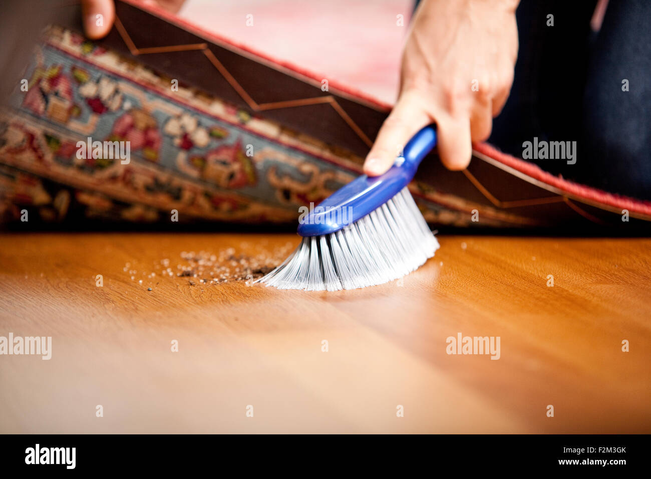 Donna spazzare sotto il tappeto Foto Stock