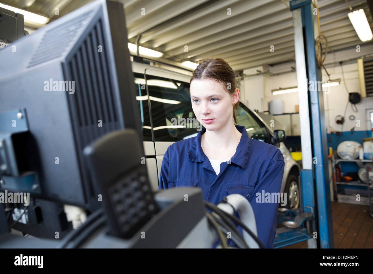 Giovane donna nel garage di riparazione auto di controllo con controllo elettronico Foto Stock